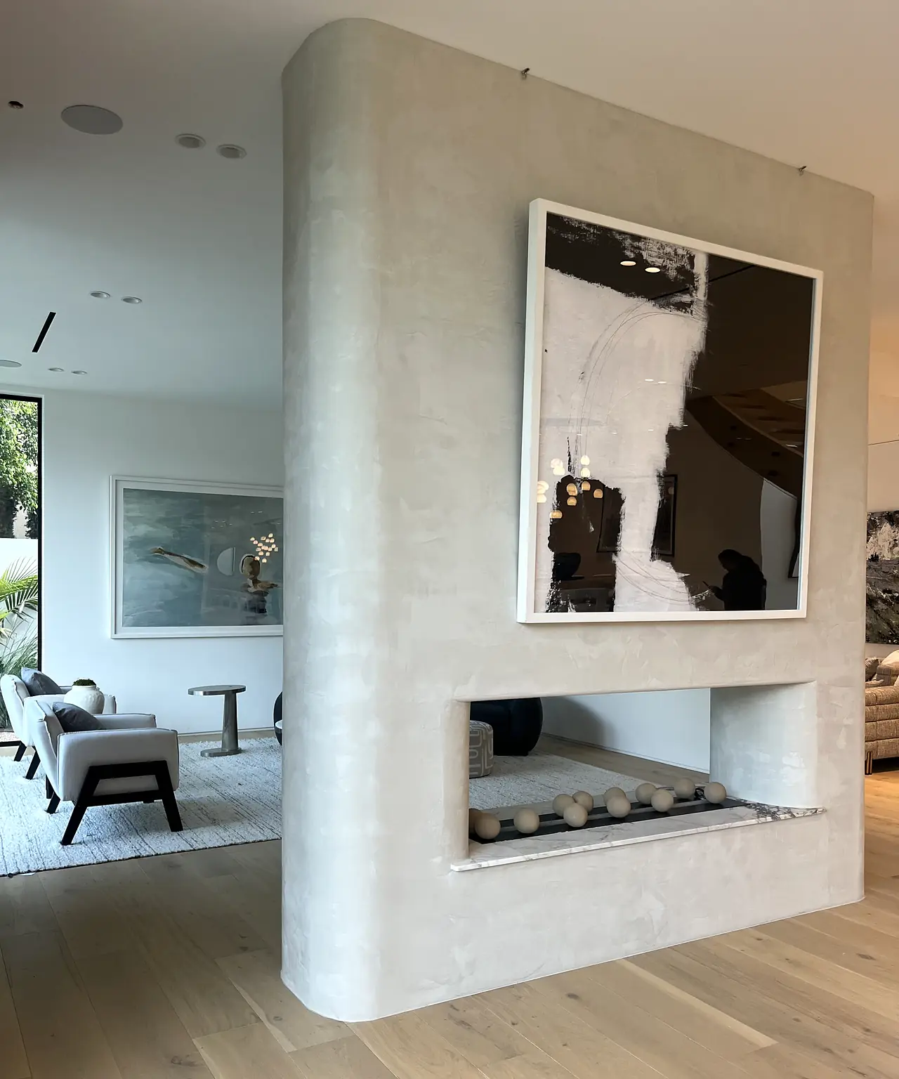 Plaster double sided fireplace in a curved column in a Los Angeles living room
