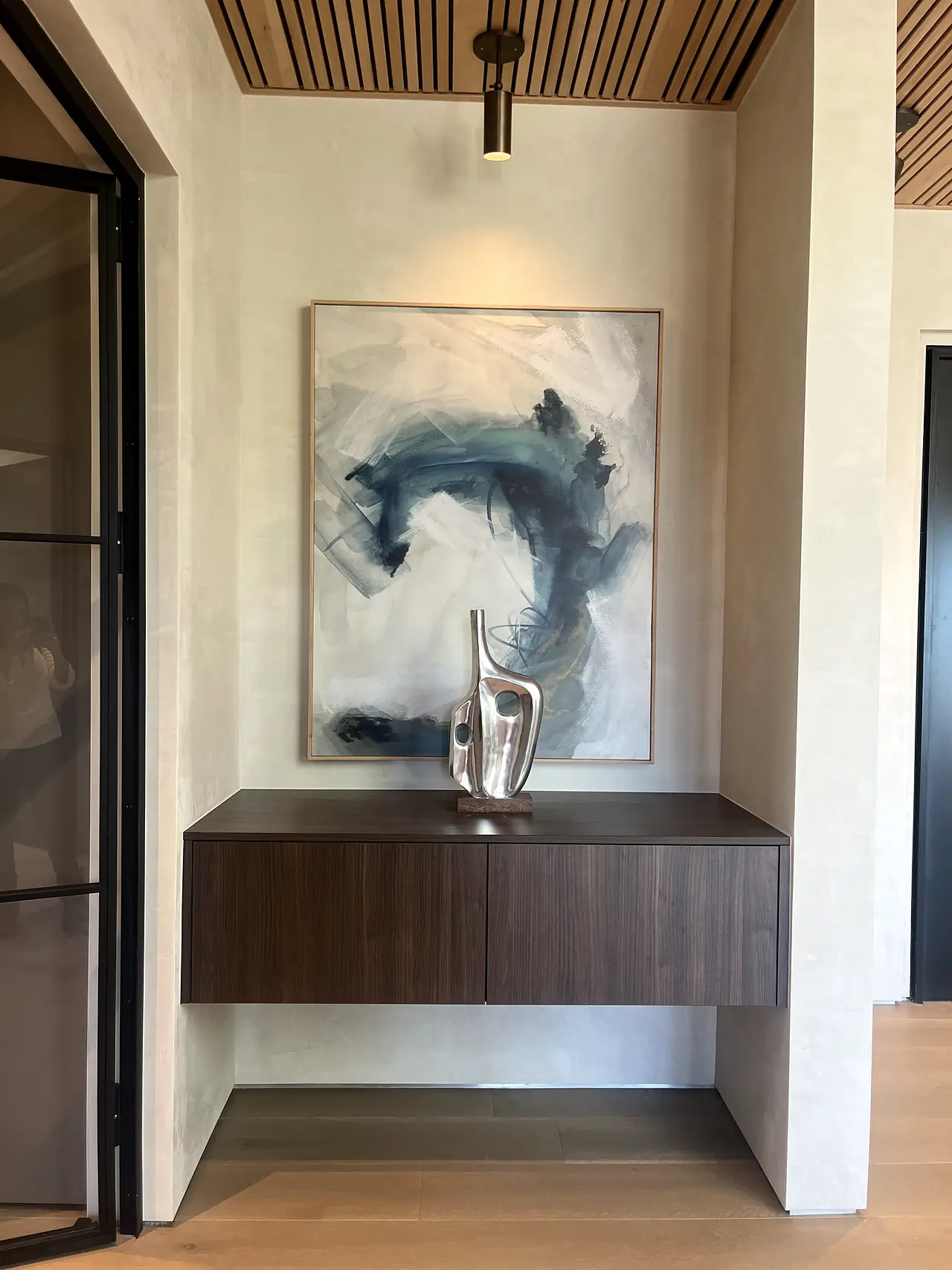 Plaster entry niche with abstract artwork and a floating console