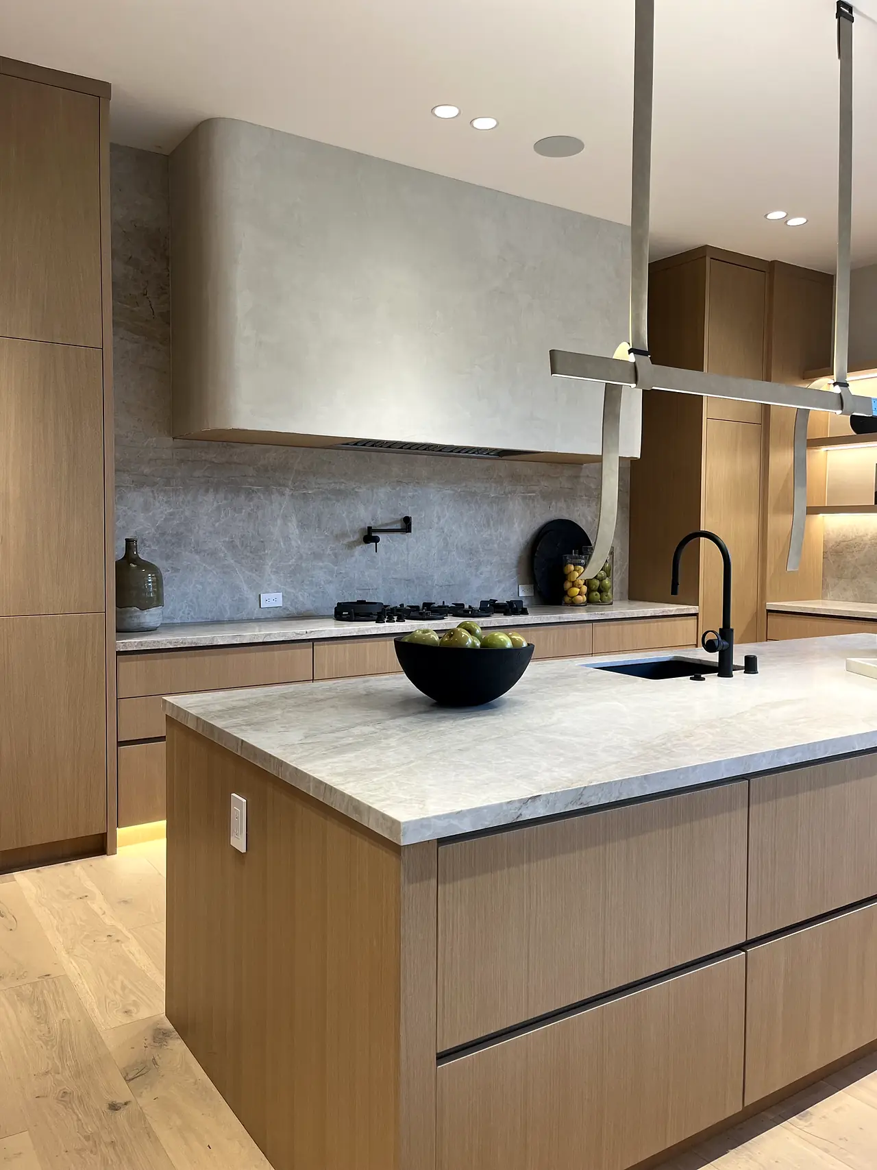 Plaster kitchen range hood above a stone backsplash in a Los Angeles home