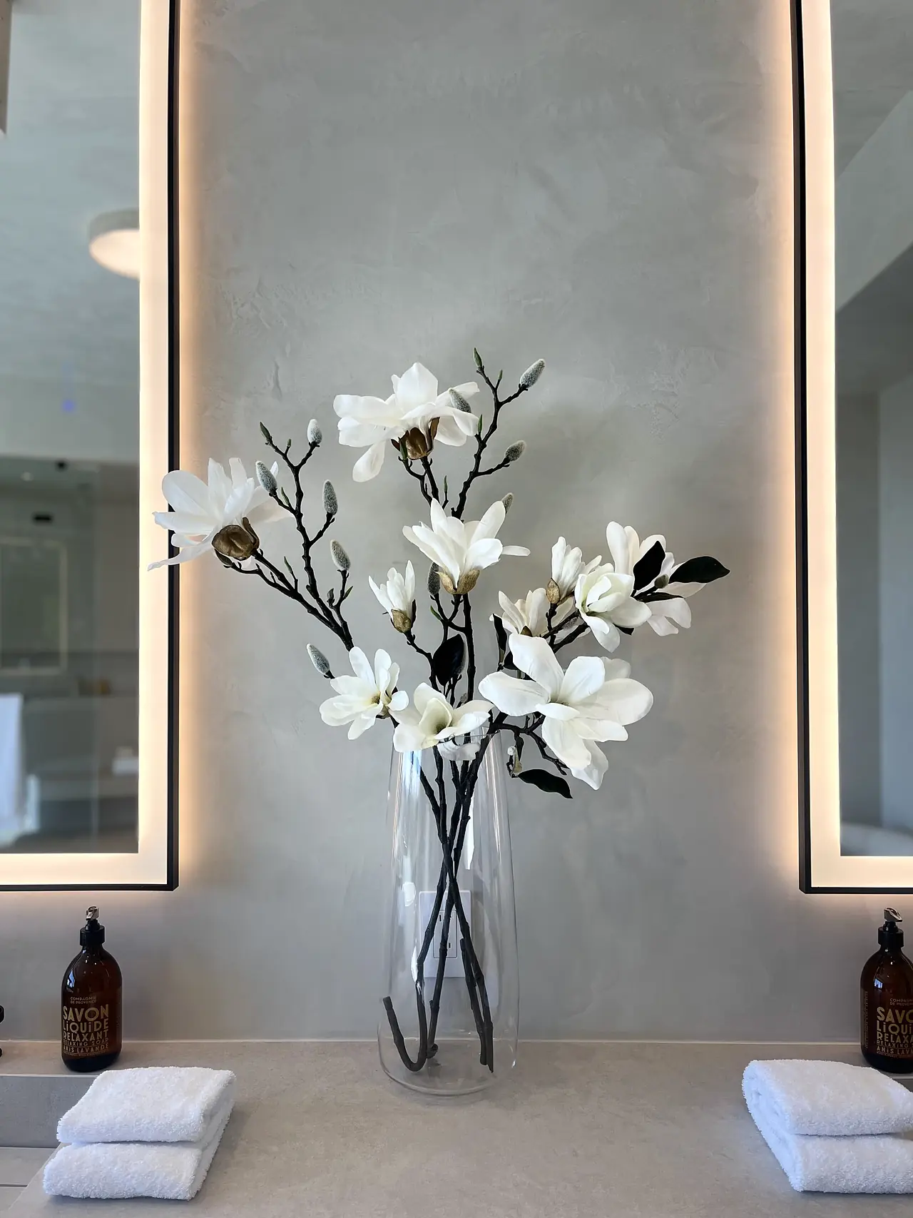 Plaster vanity wall between two backlit mirrors