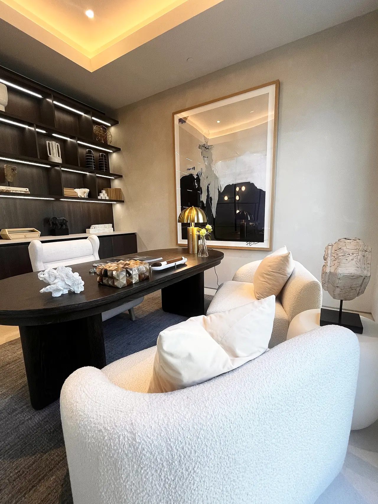 Home office with plaster walls and backlit bookshelves