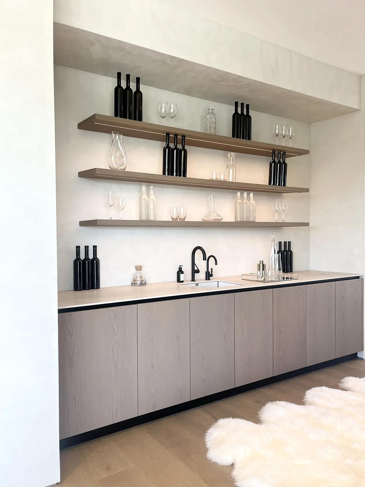Plaster wall behind a wet bar with open oak shelves